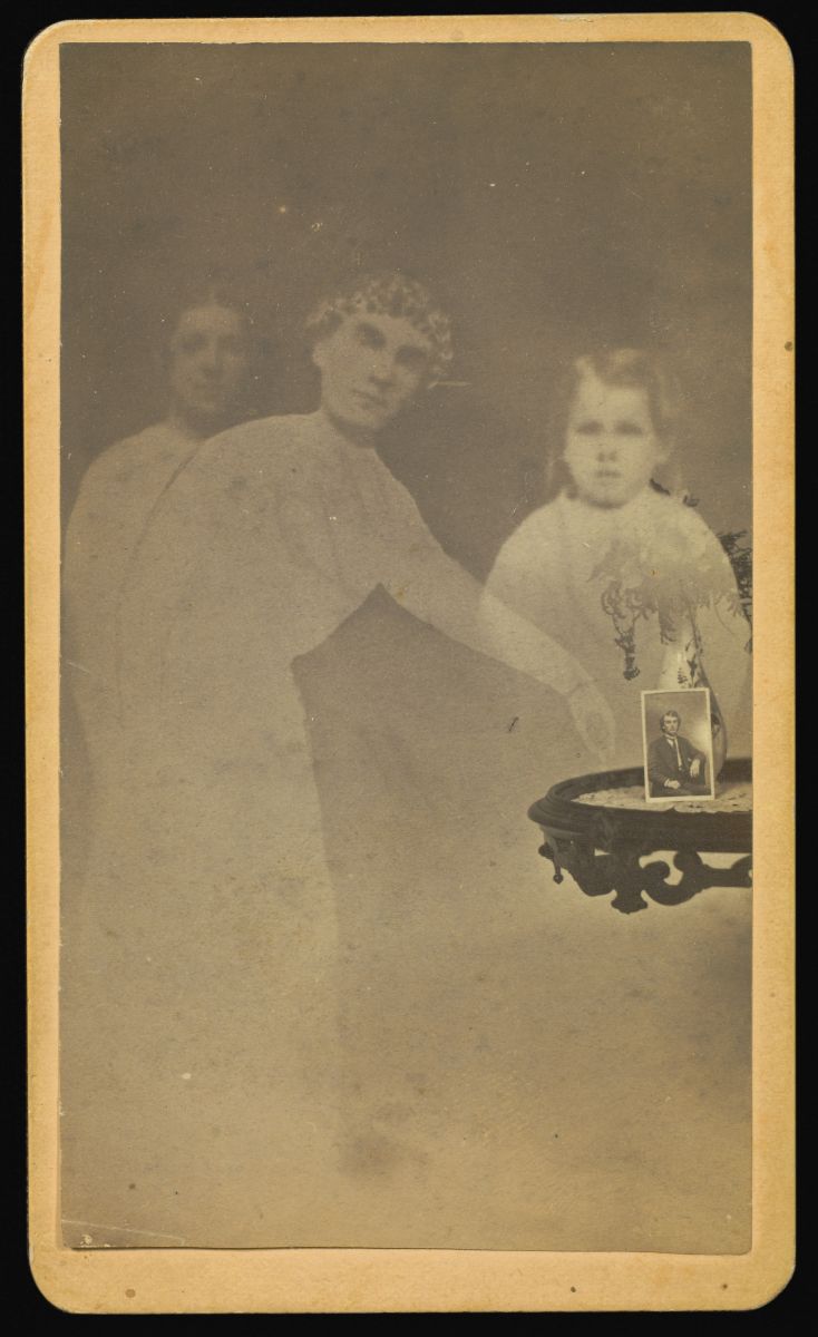 Fig. 9 William H. Mumler, Three "spirits" with a photograph on a table propped against a vase with flowers, albumen silver print, 1862-1875