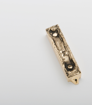 Photograph of Aleksander Prugar & Helena Czernek, New mezuzah cast from the mezuzah trace at 8 Ciepła in Białystok, Poland, on white background.