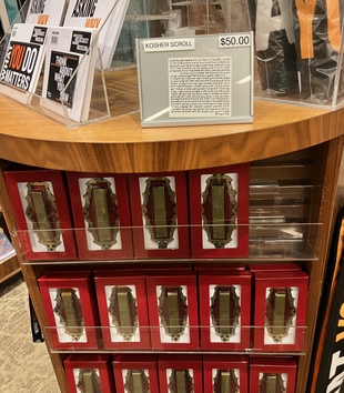 United States Holocaust Memorial Museum Store Shelf with Replicas of the "Meed" Mezuzah for Sale. Above the replicas the store offers a “kosher scroll” (klaf) for insertion into the mezuzah.