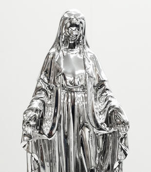 A statue of Mary, in chrome, in front of a white background.