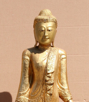 Gold buddha standing Buddha statue photographed against a cardboard background