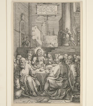 An engraving depicts Christ seated at a table with his followers. He holds a loaf of bread in each hand while one figure leans against him under the crook of his arm. The table is sunk in an archectural space down the steps from buildings in the back.