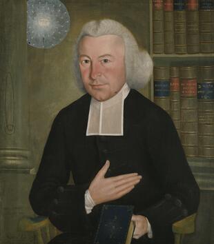 In a painting, a light-skinned clergy member in black robes sits with a bookshelf in the background and a bible in his hand. A white orb floats in the background and is painted with the Hebrew letters for “God” and the words, “All Happy in God."