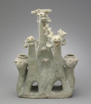 A green-glazed terracotta incense burner depicts a group of deer. They have upturned faces, flared nostrils, and floppy ears. A few of the branched antlers have broken off the animals.
