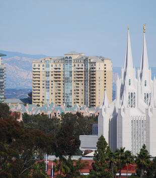 A bright white temple is located in the middle of a cityscape. It has two main spires with four smaller spires at the base of both. 