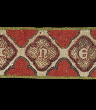 A red band is embroidered with a horizontal pattern of white diamonds enclosing red trefoils. A simple crest with a black cross is included at the end of the band.