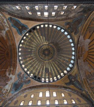 An ornate, golden dome rests on four pendentives painted with seraph and two golden half domes. Windows line the bottom of the dome to give it the apperance of hovering above.  