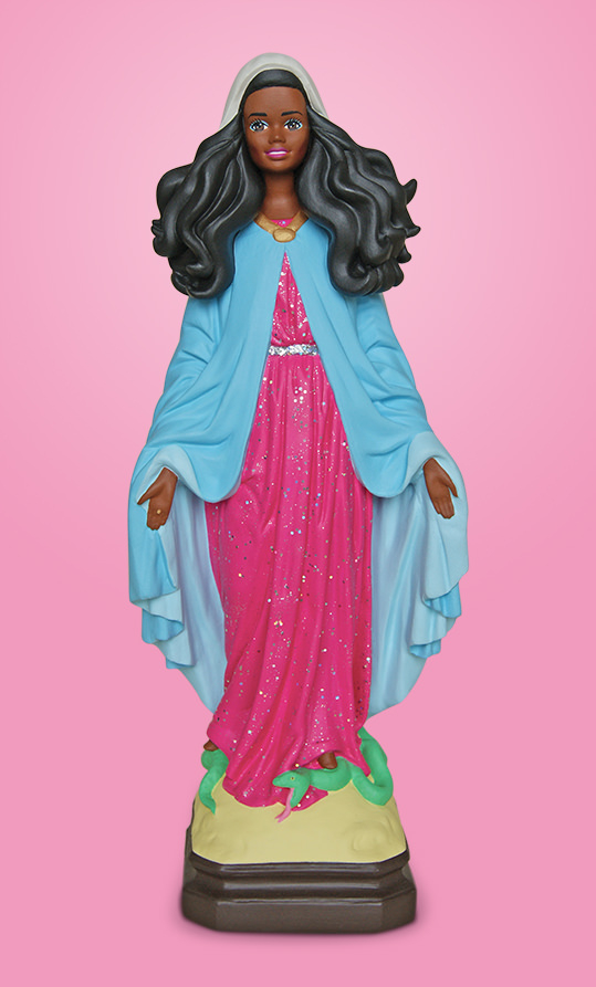 Statue in a Marian pose--arms stretched low--painted with bright colors and glitter, with a Barbie head superimposed on the figure. The Barbie head has dark skin and long dark, curly hair.