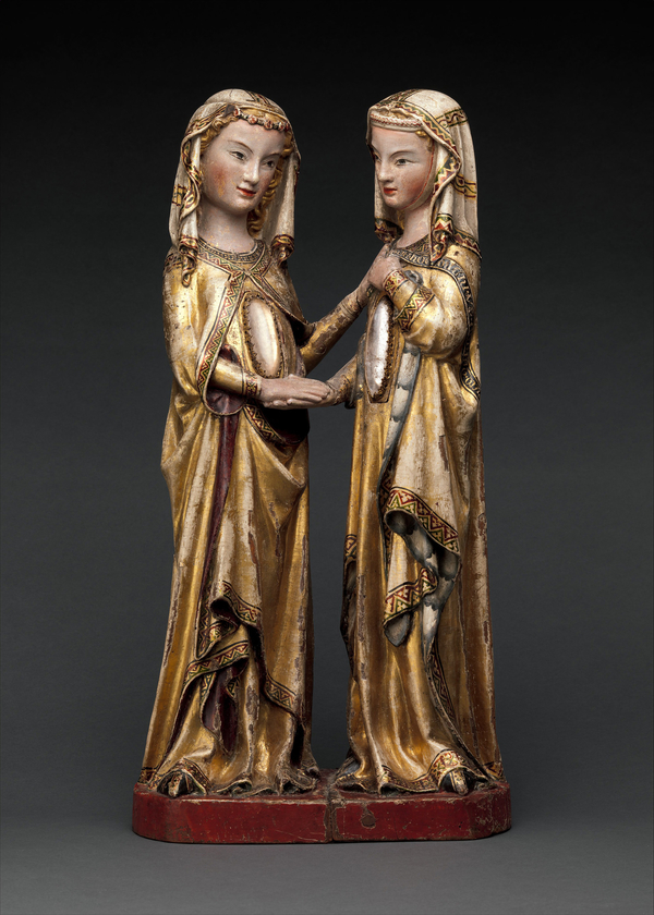 A statue of two female figures with gold robes and light skin, holding hands, with a crystal cabochon in each of their abdomens.