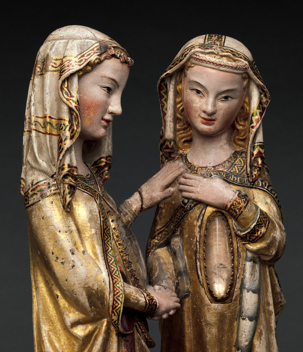 A statue of two female figures with gold robes and light skin, holding hands, with a crystal cabochon in each of their abdomens. Cropped to the waist to show detail.