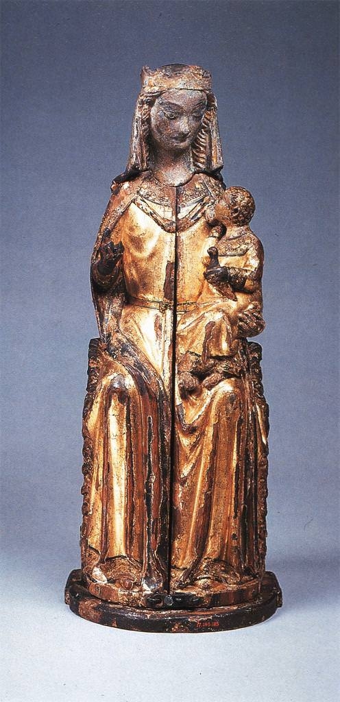 A statuette of an enthroned, light-skinned woman dressed in gold depicts her gazing down at a gold-dressed child in her arms. The figures are weathered, chipped, and slightly darkened from time.