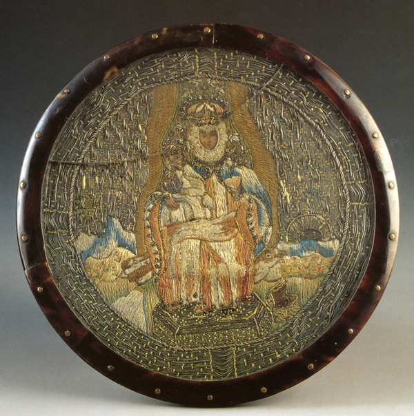 A circular tortoiseshell frame holds an embroidered image of an enthroned Virgin wearing a light blue cloak and holding the Christ child. Both wear royal coronets. A treasure chest lies open on the ground at their feet.