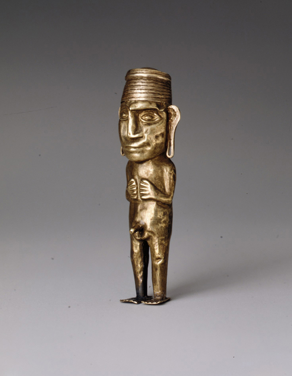 A gold figurine with an oversized head, geometric almond eyes, and large droopy ears stands on flat feet and holds his arms close to his chest. An erect penis protrudes from the figure's crotch.