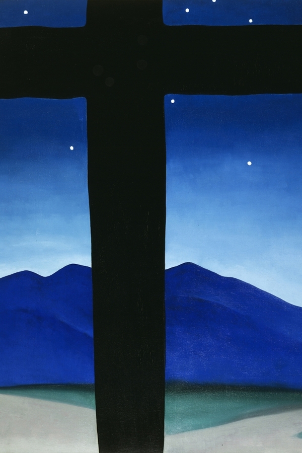 An abstract, blue mountain range and night sky shine out from behind a large, foregounded black cross.