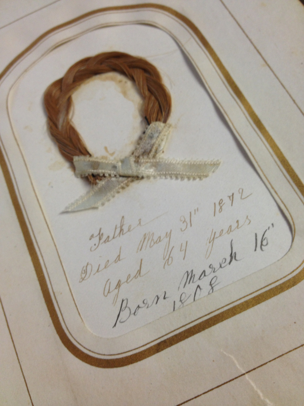 A wreath of golden hair is tied with a bow and affixed to a gold-bordered book page. Gold script reads, "Father. Died May 31st 1872. Aged 64 years." Black script below reads, "Born March 16, 1808."