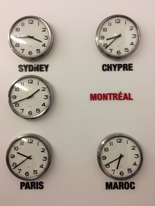 Clocks hung on a white wall showing the times of various time zones