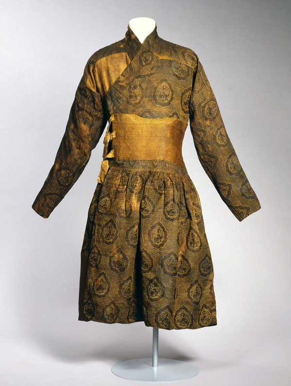 A gold-thread caftan with a side tie is patterned with drop-shaped elements holding stylized lions. These are surrounded by swastika shapes.
