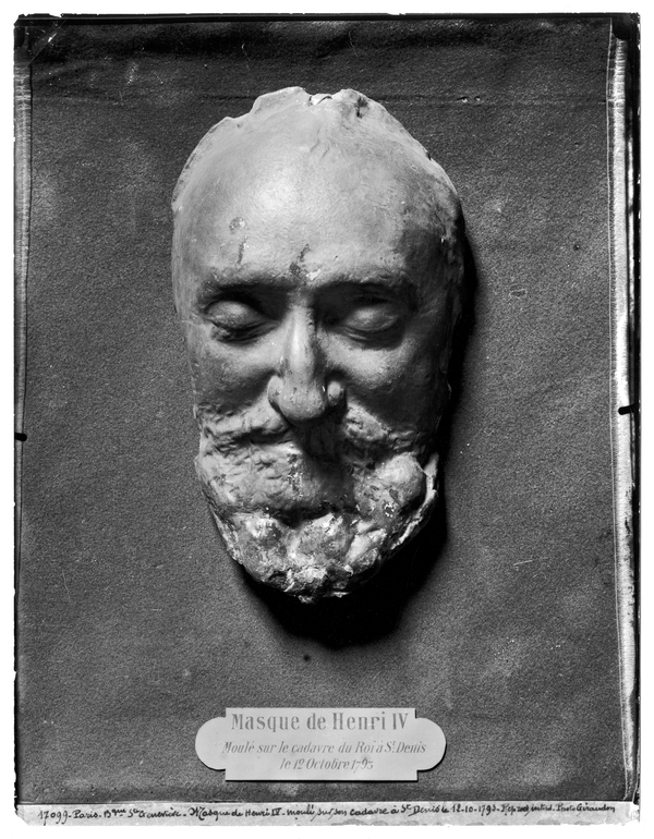 A plaster cast captures the features of a bearded and mustached man with slightly sunken, closed eyes. A metal plaque at the bottom labels the cast, "Masque de Henri IV."
