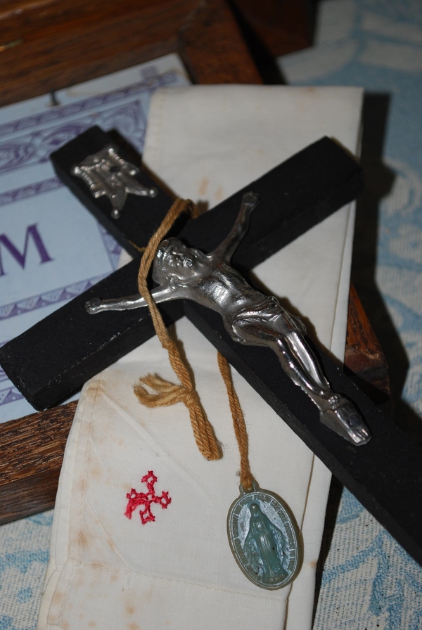 A wooden crucifix with a silver crucifix is draped with a small silver medal of a Marian image on a string 