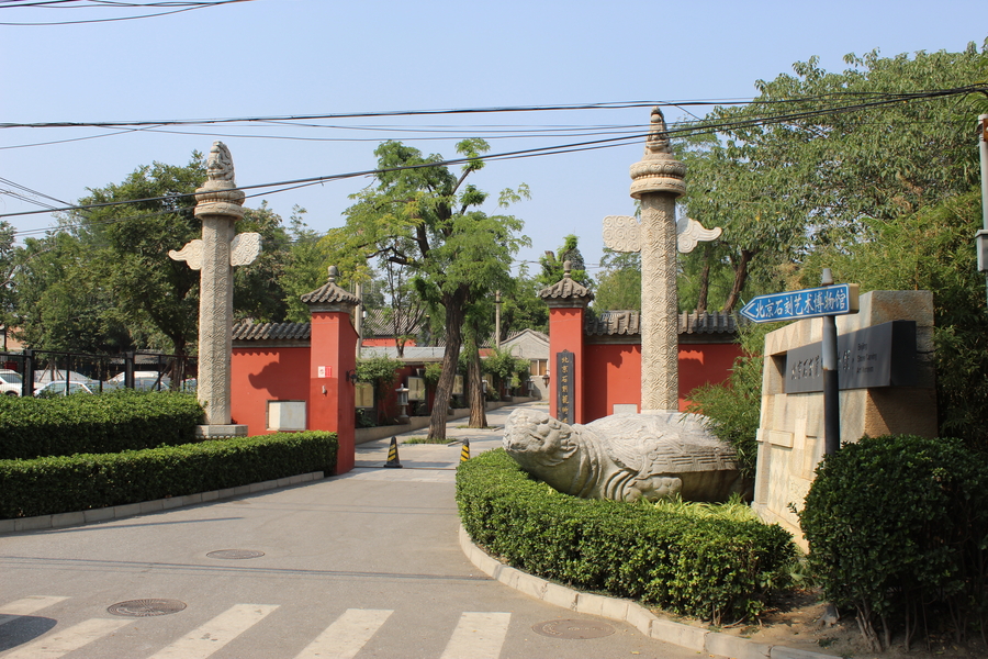 road leading to two red gates surrounded by hedges