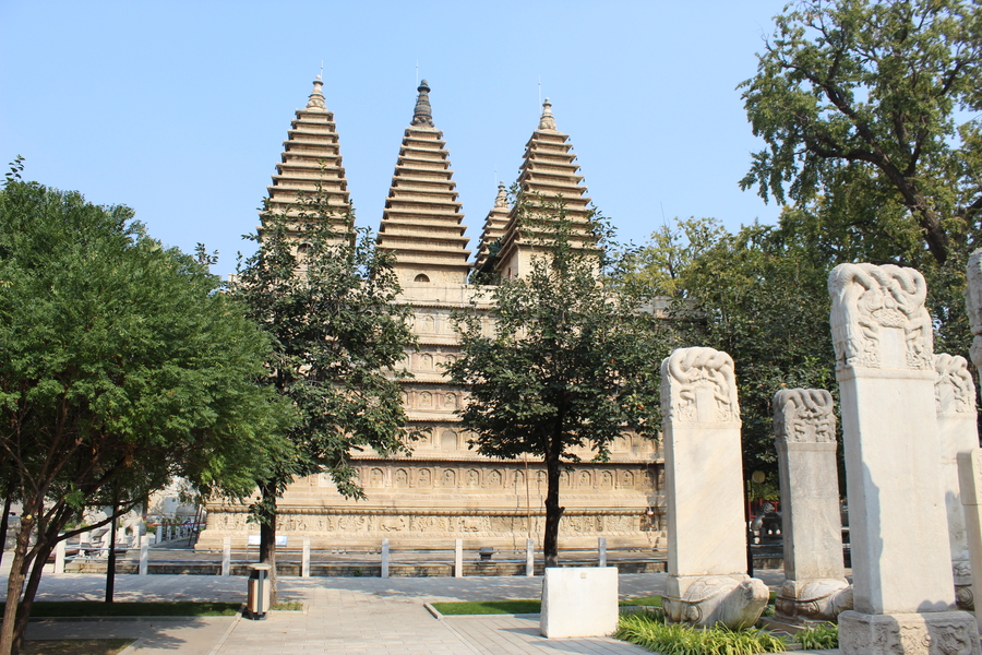  three ornate carved towers rise above a street and trees