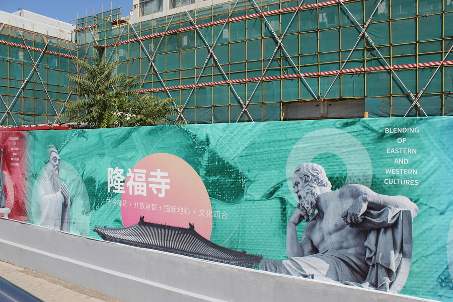  green or teal roadside ad depicting Confucius and Socrates