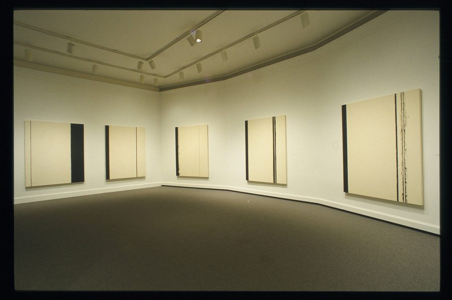 White canvases are painted with lines of different weights and positions. The paintings hang on the walls of a white gallery.