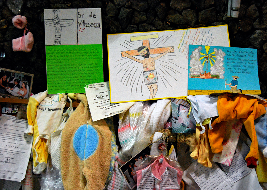 Devotional drawings and children's clothing tied to a wall