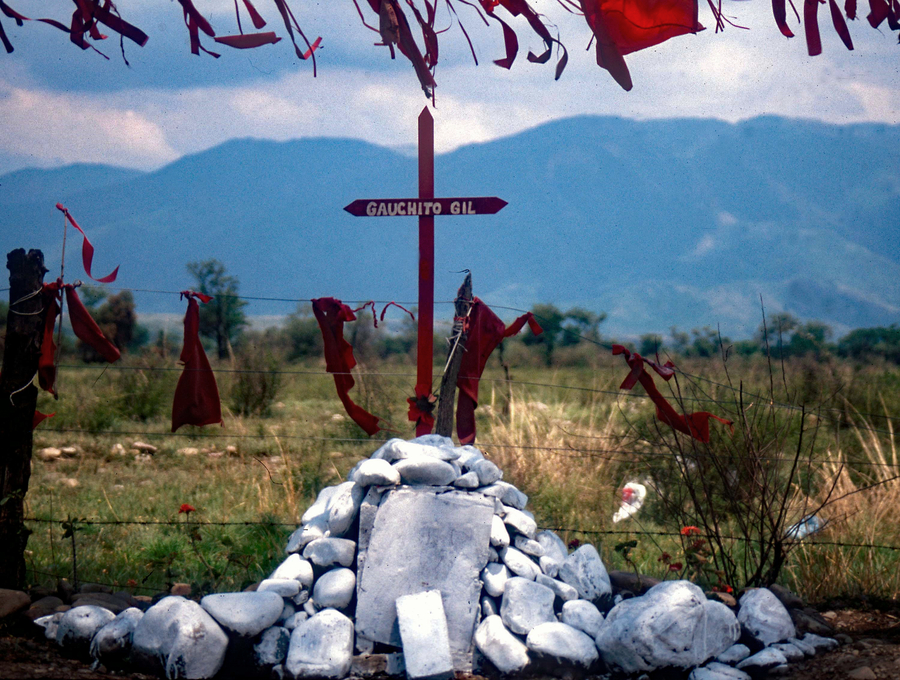 Roadside shrine made from grey rocks and a red cross 