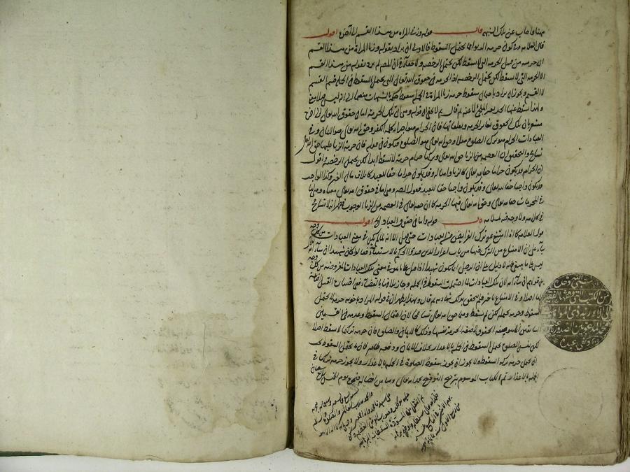 An illuminated Islamic manuscript lies open to a page of scholarly Arabic cursive in black and red.