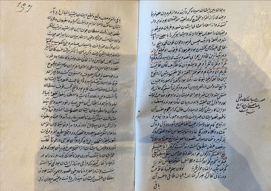 An illuminated Islamic text is open to a spread of black text with Qur’anic verses overland in red. A caption for an image not visible on the spread is included in the margins of the right page.