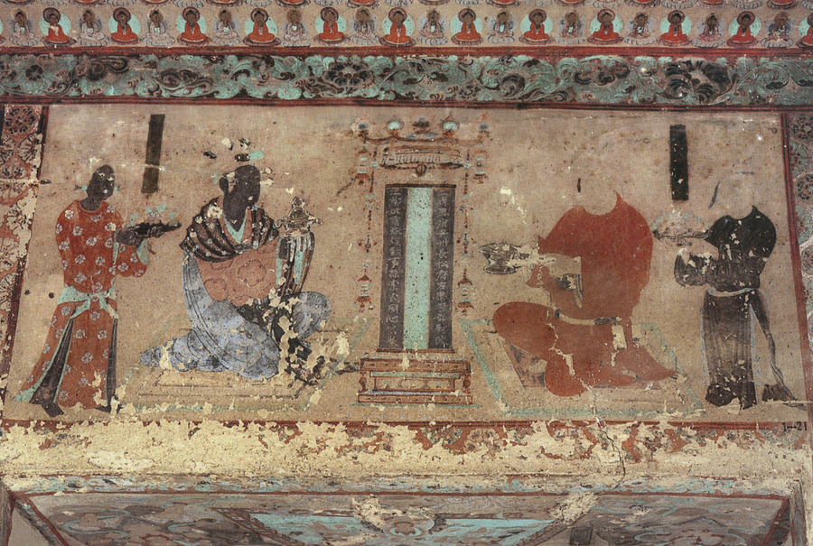 In a mural on a cave wall, robed figures gather around a painted tablet. Two larger figures kneel while their attendants hold offerrings. Much of the colorful paint has chipped off the figures.