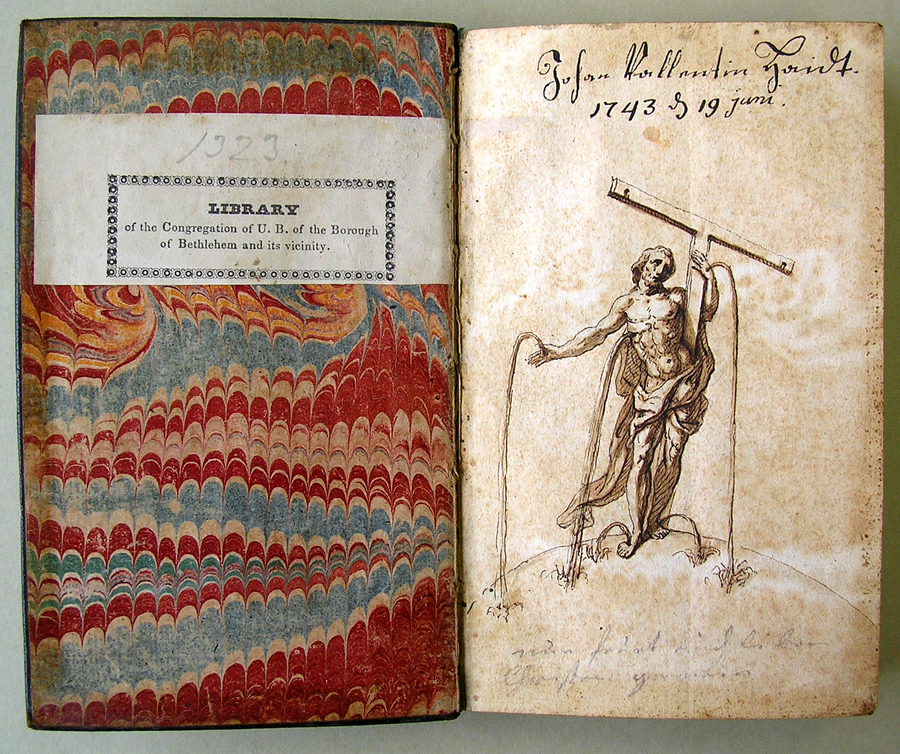 A small book lies open to expose a marbled interior cover which faces an illustrated page. This page depicts a muscular Christ in flowing drapery. He grasps a t-shaped cross in his left hand. Blood flows in long spurts from his hands, feet, and side.
